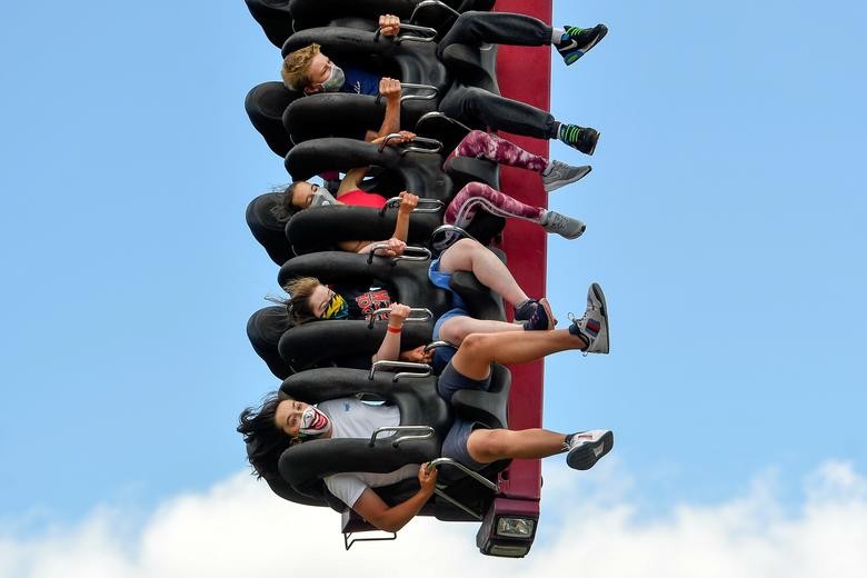 People wear compulsory protective masks as they enjoy a ride in Thorpe Park, after it reopened, in Chertsey near London, Britain. REUTERS/Toby Melville    